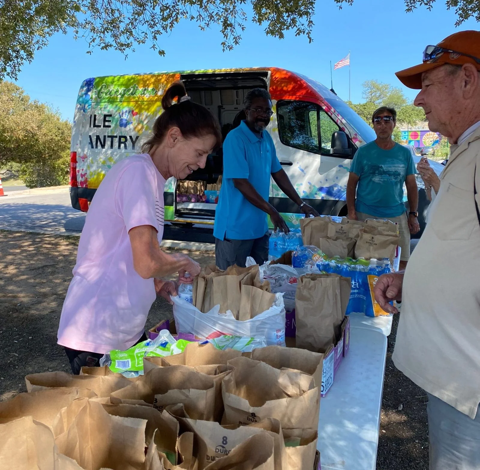 Helping Hands volunteers handing out brown-bag meals and water at the mobile pantry